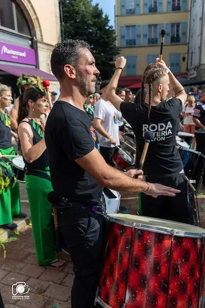 Animation de rue avec la batucada Arrête J’Adore et ses percussions brésiliennes lors d’un événement local à Lyon.
