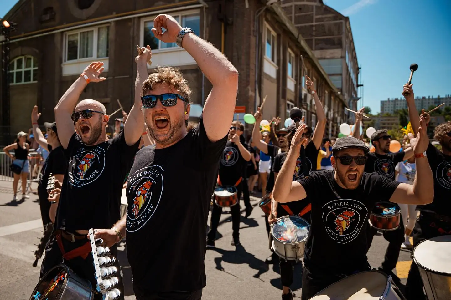 Batucada lyonnaise jouant en extérieur, ambiance samba et percussions brésiliennes.
