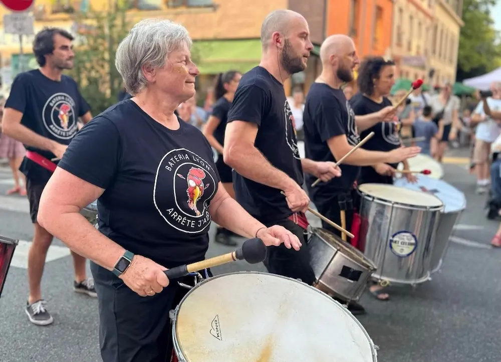 Batucada lyonnaise dynamique jouant des rythmes samba brésiliens dans les rues de la ville.
